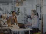 Modern glass office with two women and a man talking in a meeting
